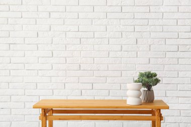 Tahta masa, bonsai ağacı ve beyaz tuğla duvarın yanındaki dekoratif figür.