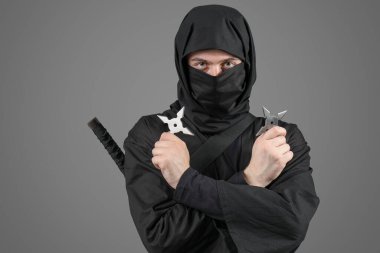 Gri arkaplanda shurikens olan erkek ninja.