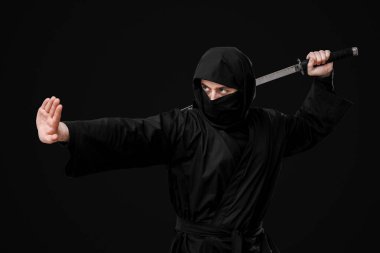Siyah arka planda kılıç taşıyan erkek ninja.