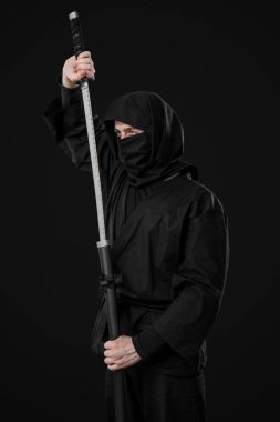 Siyah arka planda kılıç taşıyan erkek ninja.