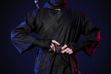 Siyah arkaplanda shurikens olan erkek ninja.