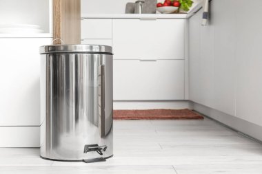 Modern mutfağın içindeki masanın yanındaki metal çöp tenekesi.