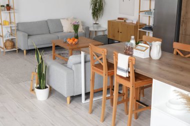 Ada masası ve gri koltukları olan açık planlı bir mutfak.