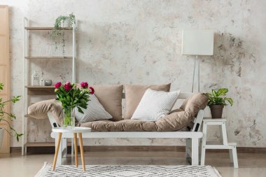 Kırmızı şakayıklı vazo, kanepe ve raflar oturma odasında.