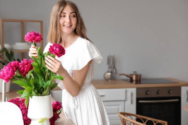 Mutfakta şakayık çiçekleri olan güzel bir kadın.