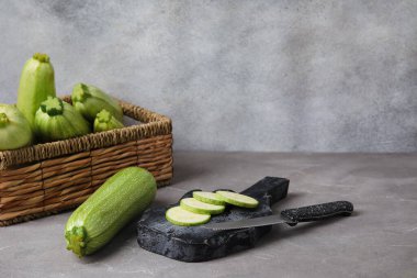 Taze yeşil kabaklı hasır kutu ve gri arka planda dilimler.