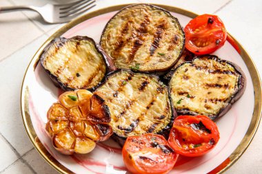 Hafif arka planda leziz ızgara patlıcan ve domates tabağı, yakın plan.