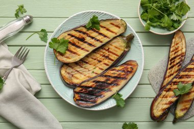 Lezzetli ızgara patlıcan tabağı ve yeşil ahşap arka planda maydanoz.