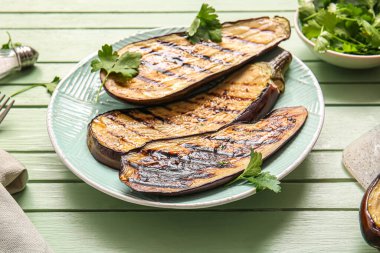 Lezzetli ızgara patlıcan tabağı ve yeşil ahşap arka planda maydanoz.