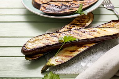 Yeşil ahşap arka planda leziz ızgara patlıcanlar.