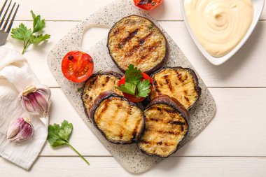 Beyaz ahşap arka planda leziz ızgara patlıcan, sos ve domates.