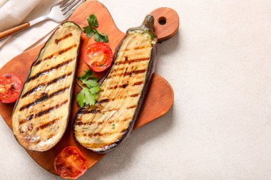 Hafif arka planda leziz ızgara patlıcanlar, domatesler ve otlarla dolu bir pano.