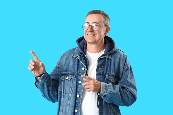 Starší Muž Brýlích Ukazuje Něco Modrém Pozadí — Stock fotografie