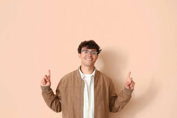 Νεαρός Άνδρας Κομψά Γυαλιά Που Δείχνει Κάτι Μπεζ Φόντο — Φωτογραφία Αρχείου