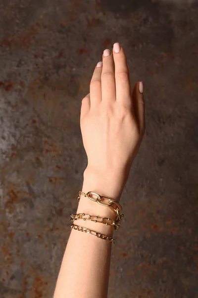 Kvinna Hand Med Olika Vackra Gyllene Armband Grunge Brun Bakgrund — Stockfoto