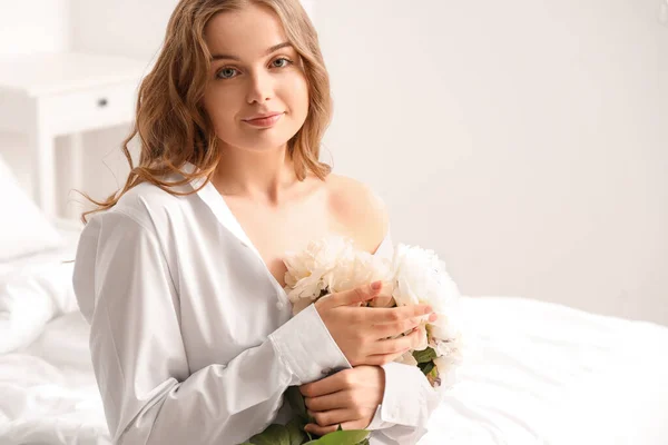 寝室に牡丹の花の花束を持つ美しい若い女性 — ストック写真