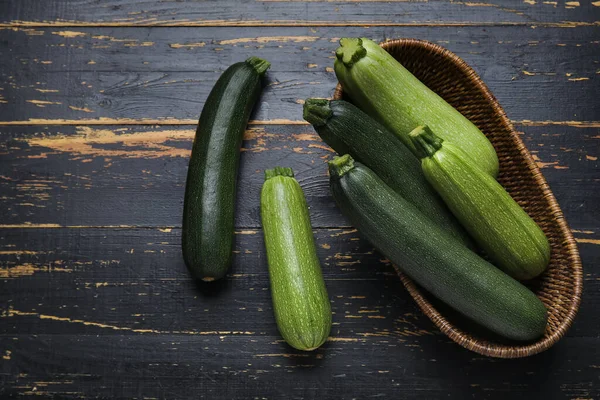 Wicker Skål Med Färsk Grön Zucchini Svart Trä Bakgrund — Stockfoto