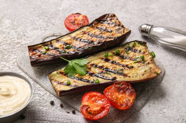 Lezzetli ızgara patlıcan, domates ve gri arka planda sos.