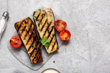 Gri arka planda leziz ızgara patlıcan ve domates.