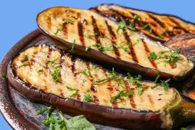 Mavi arka planda lezzetli ızgara patlıcan tabağı, yakın plan.