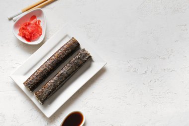 Hafif arka planda lezzetli maki dürümleri, zencefil ve soya soslu tabak.