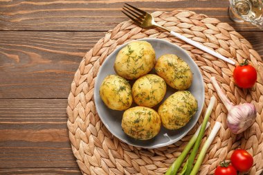 Ahşap zemin üzerinde dereotu ve yeşil soğanlı haşlanmış bebek patatesler.