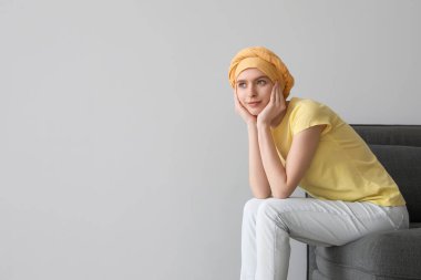 Kemoterapiden sonra arka planda oturan genç bir kız.