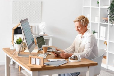 Ofiste tablet bilgisayarla çalışan olgun bir kadın programcı.