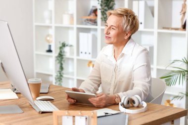 Ofiste tablet bilgisayarla çalışan olgun bir kadın programcı.