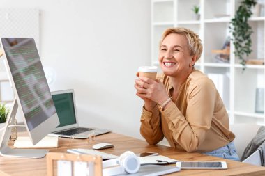 Ofiste çalışan olgun bir kadın programcı ve bir fincan kahve.