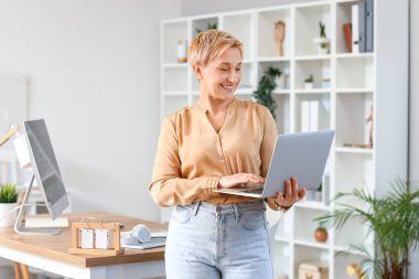 Dizüstü bilgisayarı olan olgun bir kadın programcı.