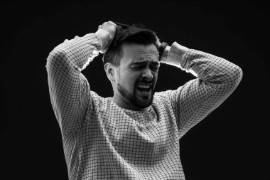 Genç adam siyah arka planda panik atak geçiriyor.