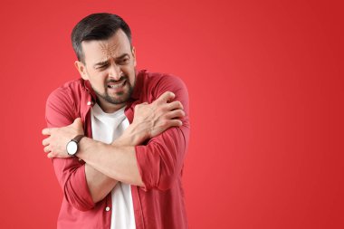 Genç adam kırmızı arka planda panik atak geçiriyor.