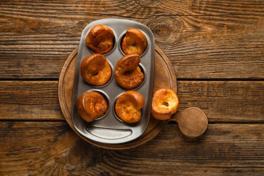 Ahşap arka planda lezzetli Yorkshire pudingi olan teneke fırın.