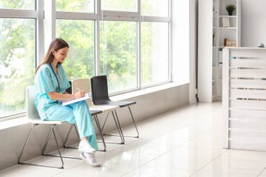 Kadın stajyer doktor hastanede panoya yazı yazıyor.