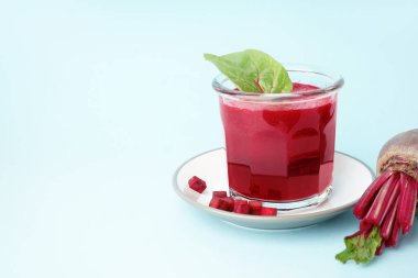 Bir bardak sağlıklı pancar suyu ve mavi arka planda ıspanak.