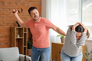 Kızgın koca evde karısını kemerle dövüyor. Aile içi şiddet kavramı