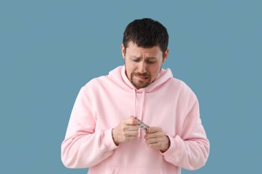 Genç adam mavi arka planda panik ataktan haplar alıyor.