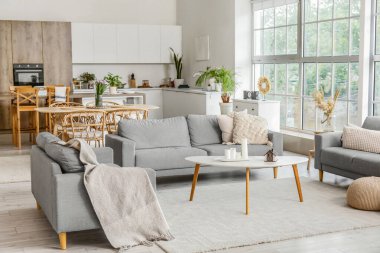 Gri kanepeleri ve kahve sehpası olan açık mutfak.