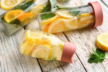 Beyaz ahşap arka planda limonlu ve naneli spor şişeleri