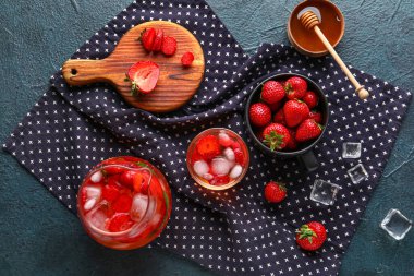 Siyah arka planda çilekli bir bardak ve bir sürahi eritilmiş su.