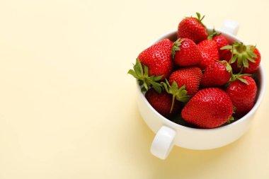 Sarı arka planda taze çilekli kase.