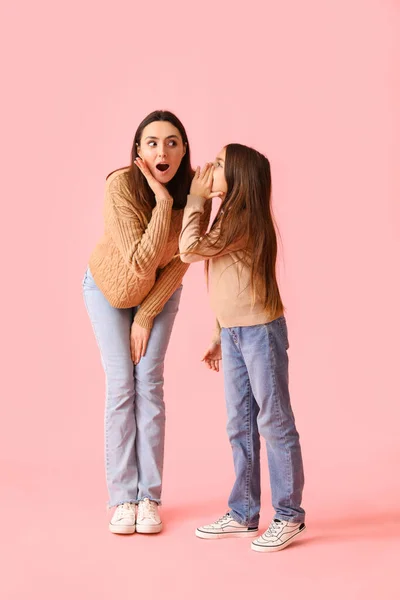 女の子言う秘密へ彼女のショックの母親オンピンクの背景 — ストック写真