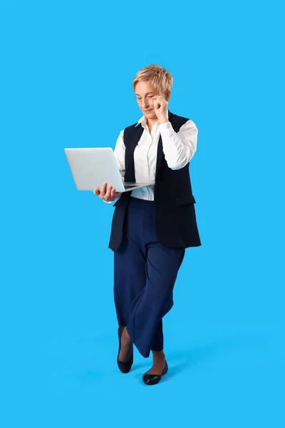 stock image Mature female programmer working with laptop on blue background