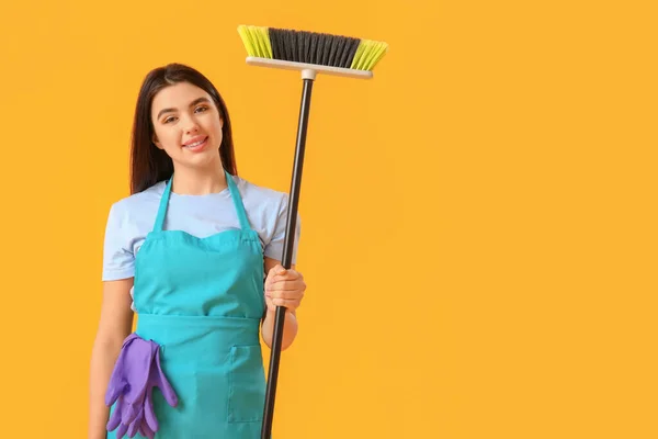 黄色の背景にほうきと女性清掃員 — ストック写真