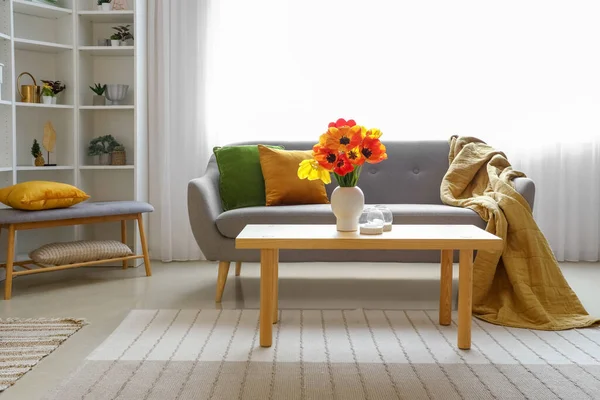 stock image Interior of light living room with cozy grey sofa and tulip flowers on coffee table