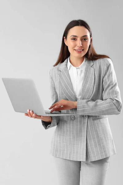 Şık Takım Elbiseli Genç Kadını Arka Planda Dizüstü Bilgisayar Kullanıyor — Stok fotoğraf