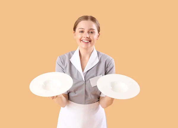 漂亮的年轻女服务员 带着米色背景的空盘子 — 图库照片