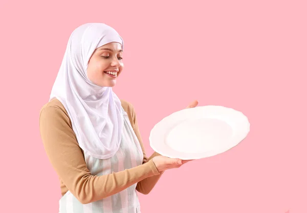 ピンクの背景に空のプレートを持つ美しいアラビア人女性 — ストック写真