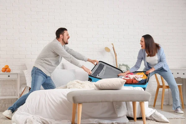 ベッドルームで戦うスーツケースと怒っているカップル 家庭内暴力の概念 — ストック写真
